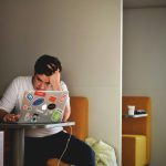 man wearing white top using MacBook