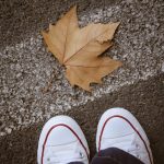 Autumn Leaf Near Sneakers on Asphalt Surface