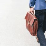 person walking holding brown leather bag