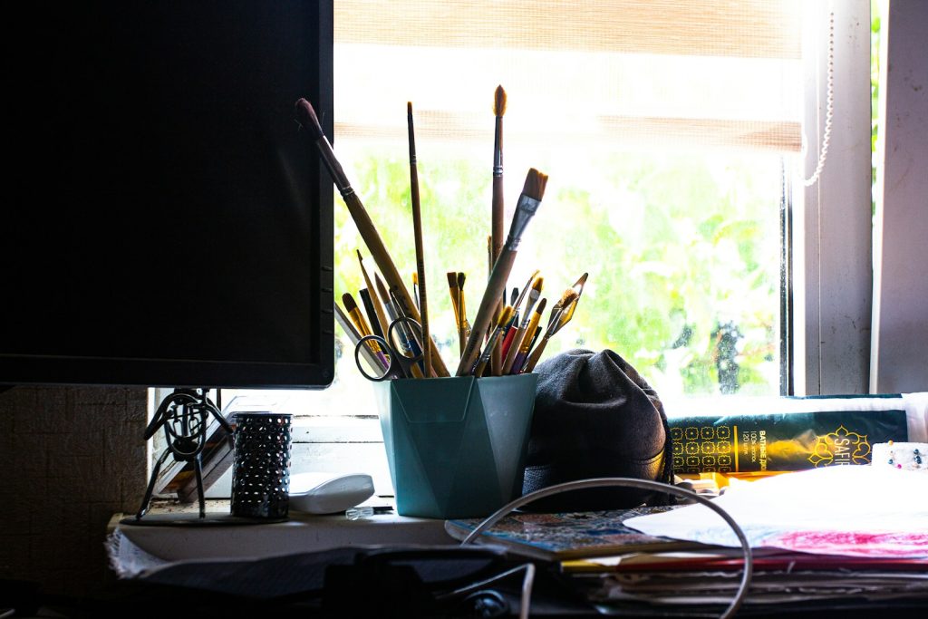 a desk with a computer monitor and a bunch of pens