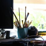 a desk with a computer monitor and a bunch of pens