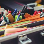 assorted pen and colored papers in organizer case