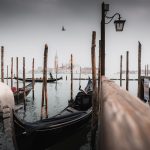 A row of gondolas sitting next to a wooden pier