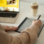 a woman is writing on a tablet with a pen